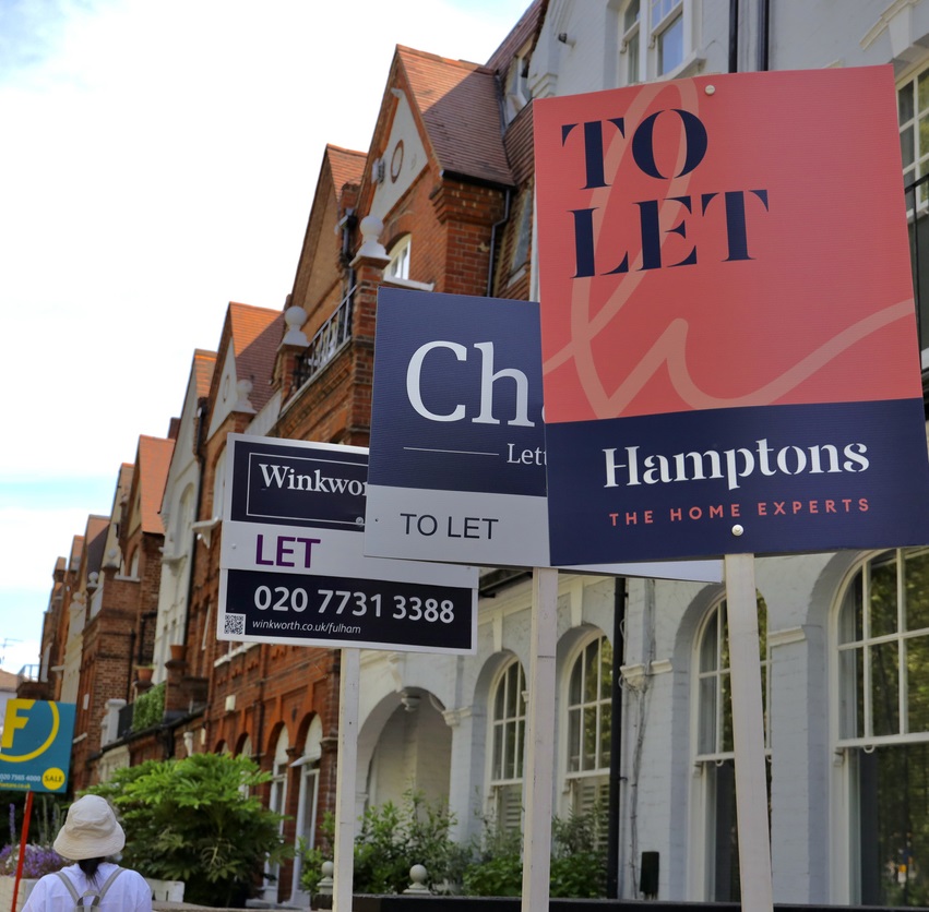Row of houses with to let and for sale signs outside them